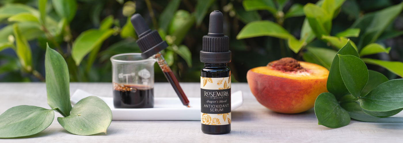Dragon's Blood Antioxidant Serum with half a peach and green leaves