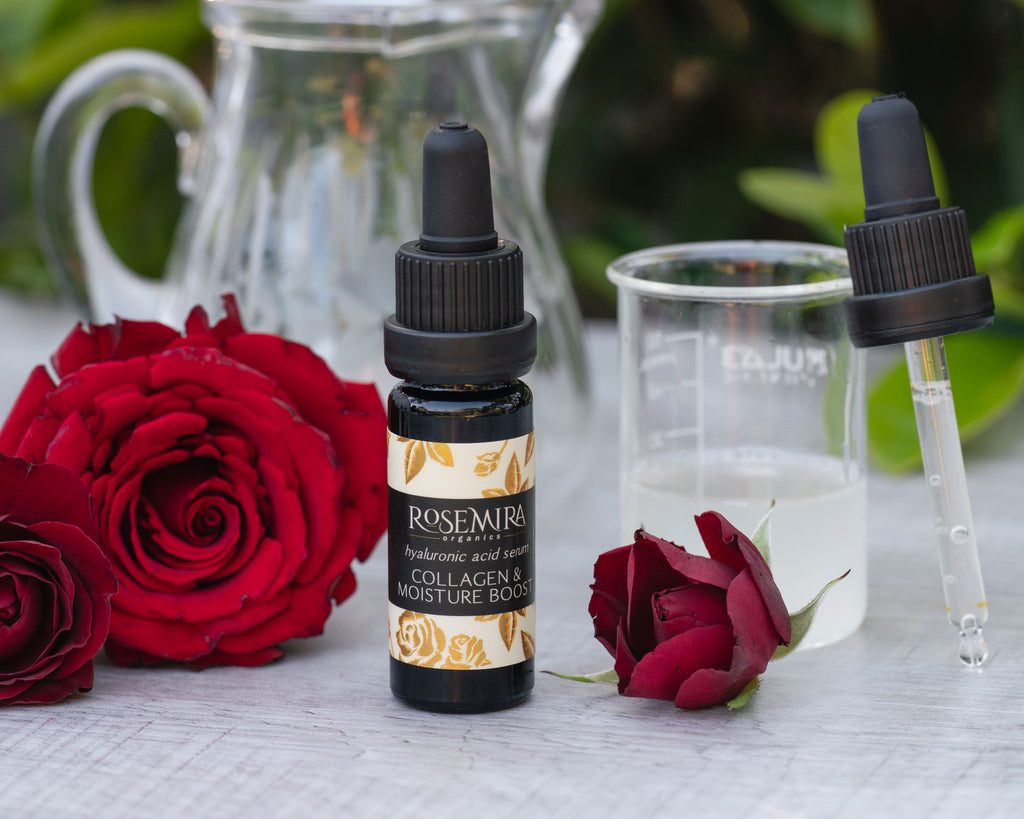 A black bottle of Hyaluronic Acid Serum with a beaker and tincture of clear serum liquid and red roses.
