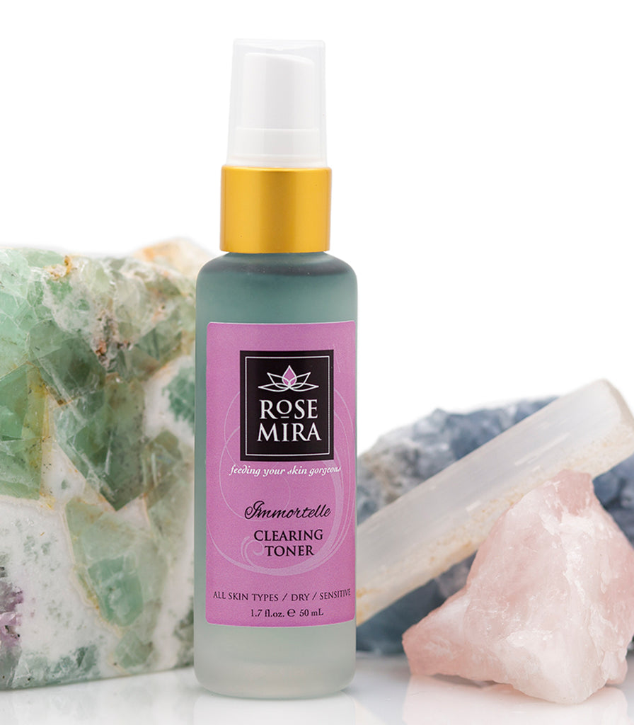 A clear bottle of Immortelle Clearing Toner with crystals