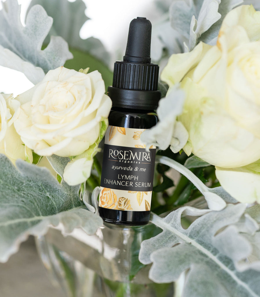 Ayurveda and Me Lymph Enhancer Serum in a bouquet of white roses and sage leaves.