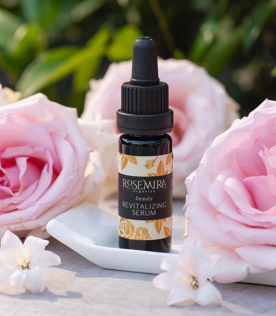 Organic revitalizing serum on white tray with pink flowers