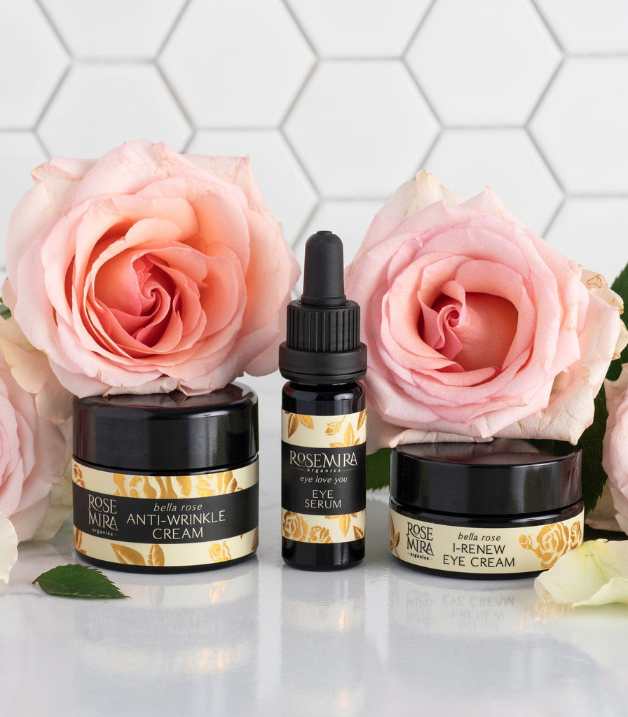 Bella Rose Anti-Wrinkle Cream, Eye Love You Eye Serum, and Bella Rose Eye Cream with pink roses on reflective counter