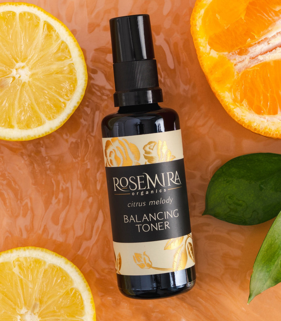 Balancing Toner with orange and lemon slices on wet orange surface.