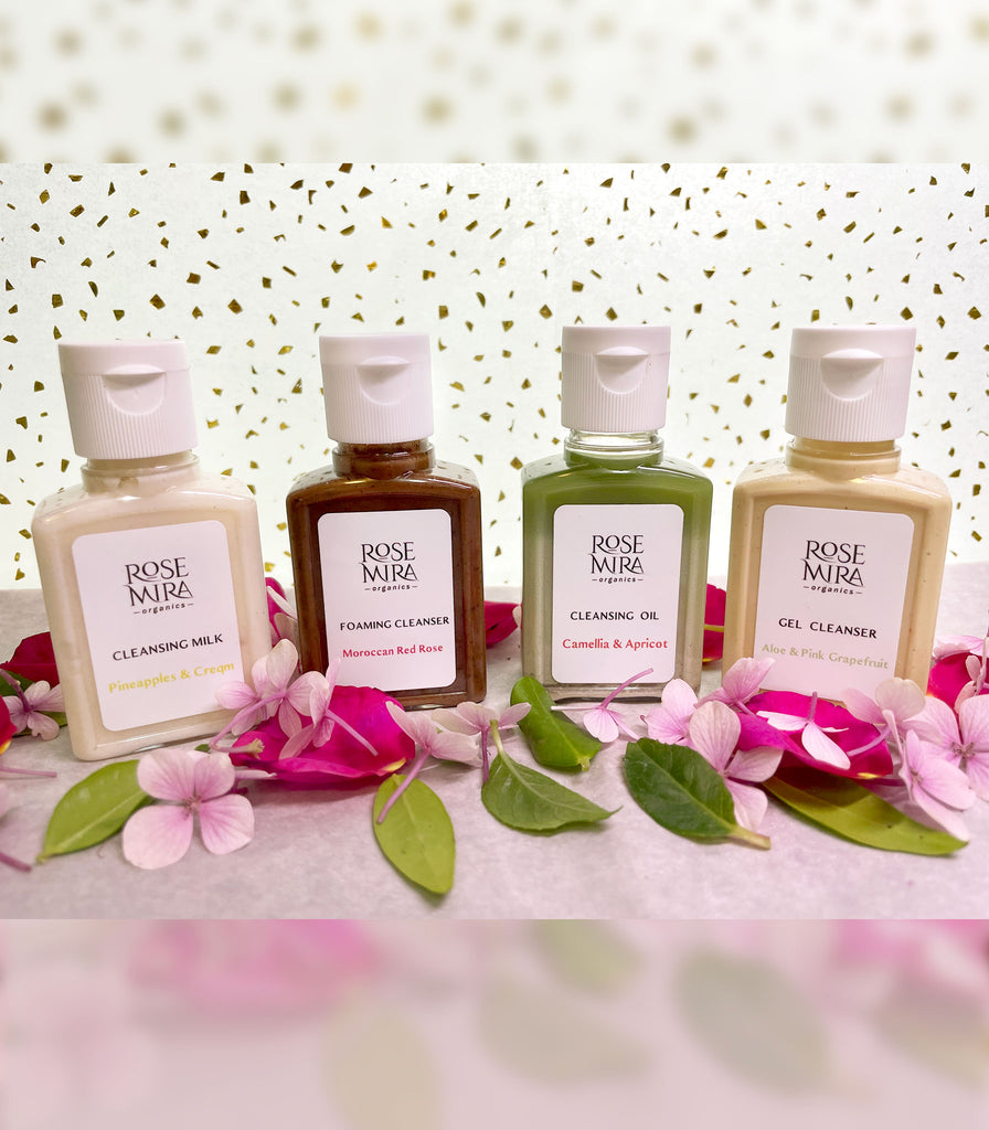 Cleanser Travel Kit with four organic cleansers, pink flowers, green leaves, and gold spotted paper.