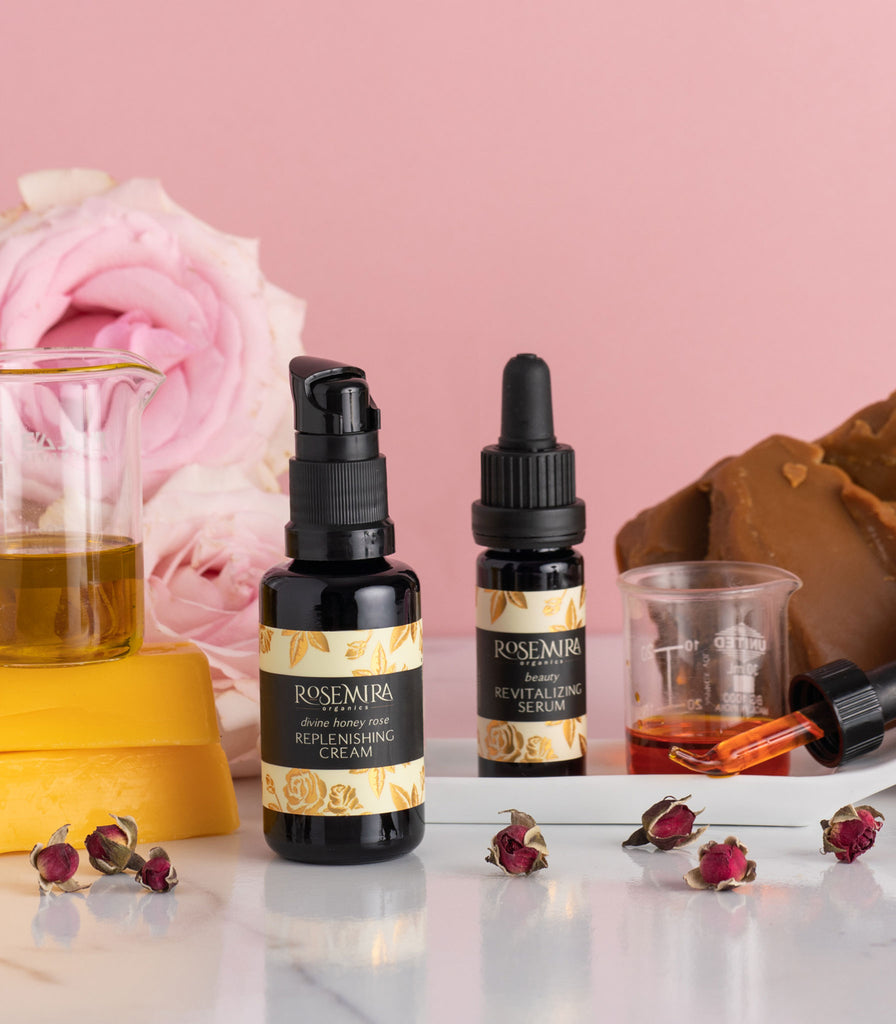 Replenishing Cream and Beauty Revitalizing Serum with beakers of richly-colored serums, dried rosebuds, and ingredients.