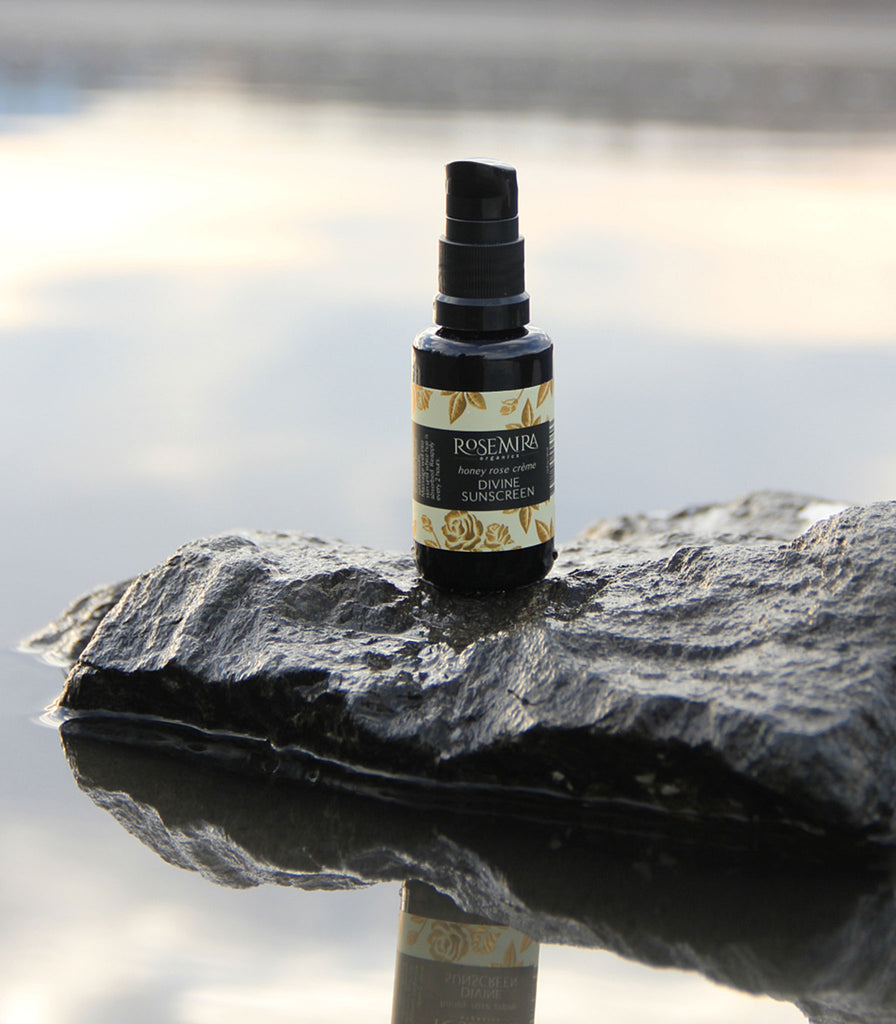 Honey Rose Creme Divine Sunscreen on a rock in reflective water