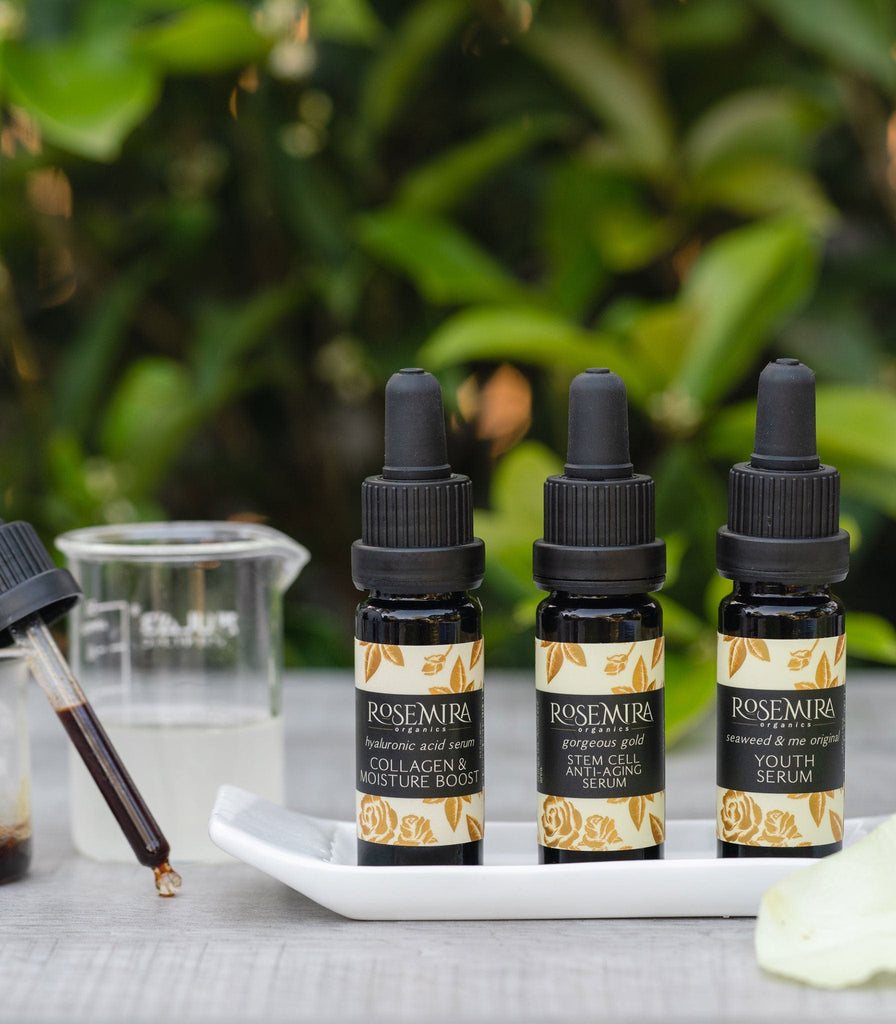 Three popular Rosemira serums on a white tray with a tincture of dark gold serum liquid.