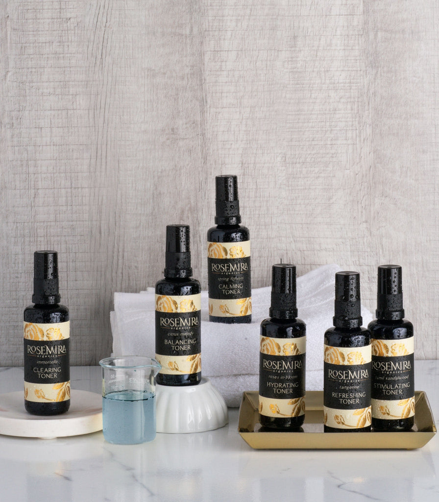 A collection of organic natural toner bottles on white counter with white towel and bowl.