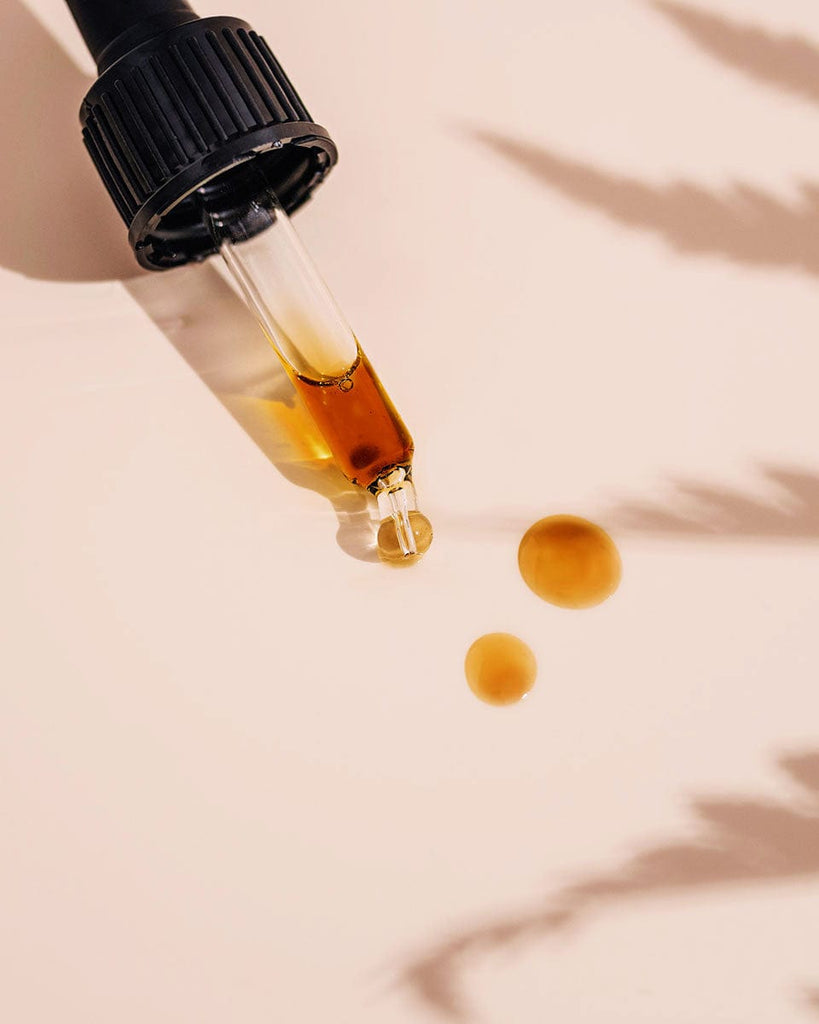 Applying Rosemira serum drops with gold background for glowing skin