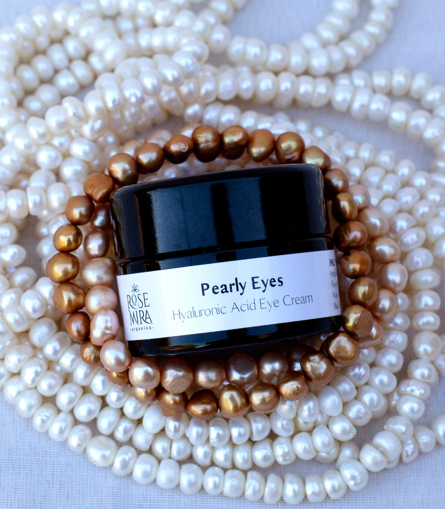 A bottle of Pearly Eyes resting in several strands of pearls