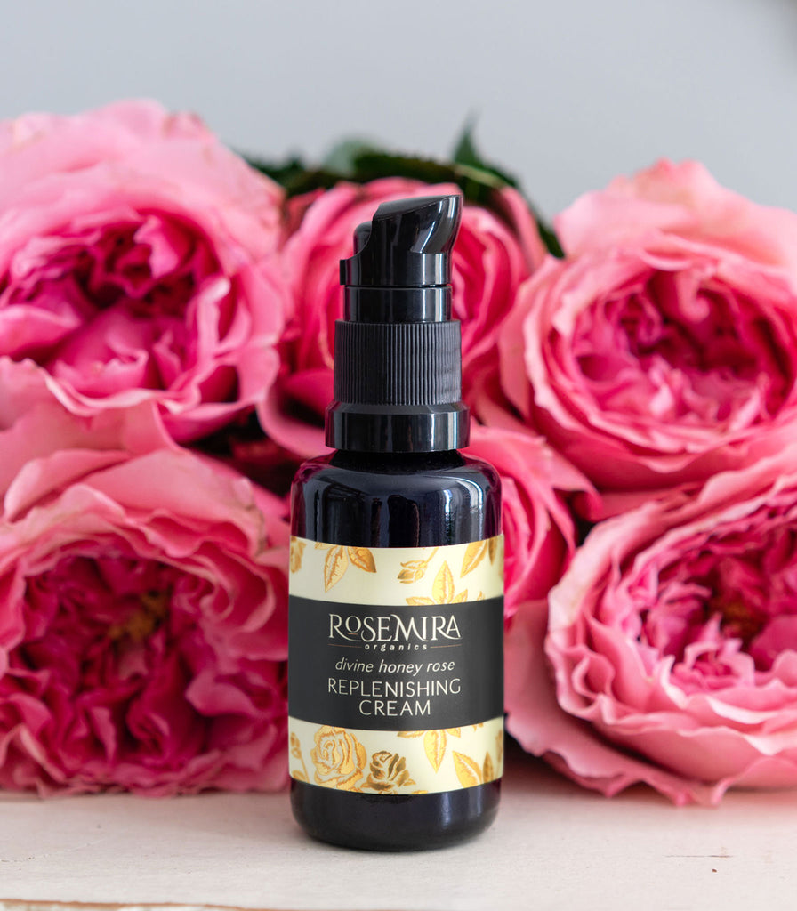Rosemira face cream on a white table with a bouquet of pink roses.
